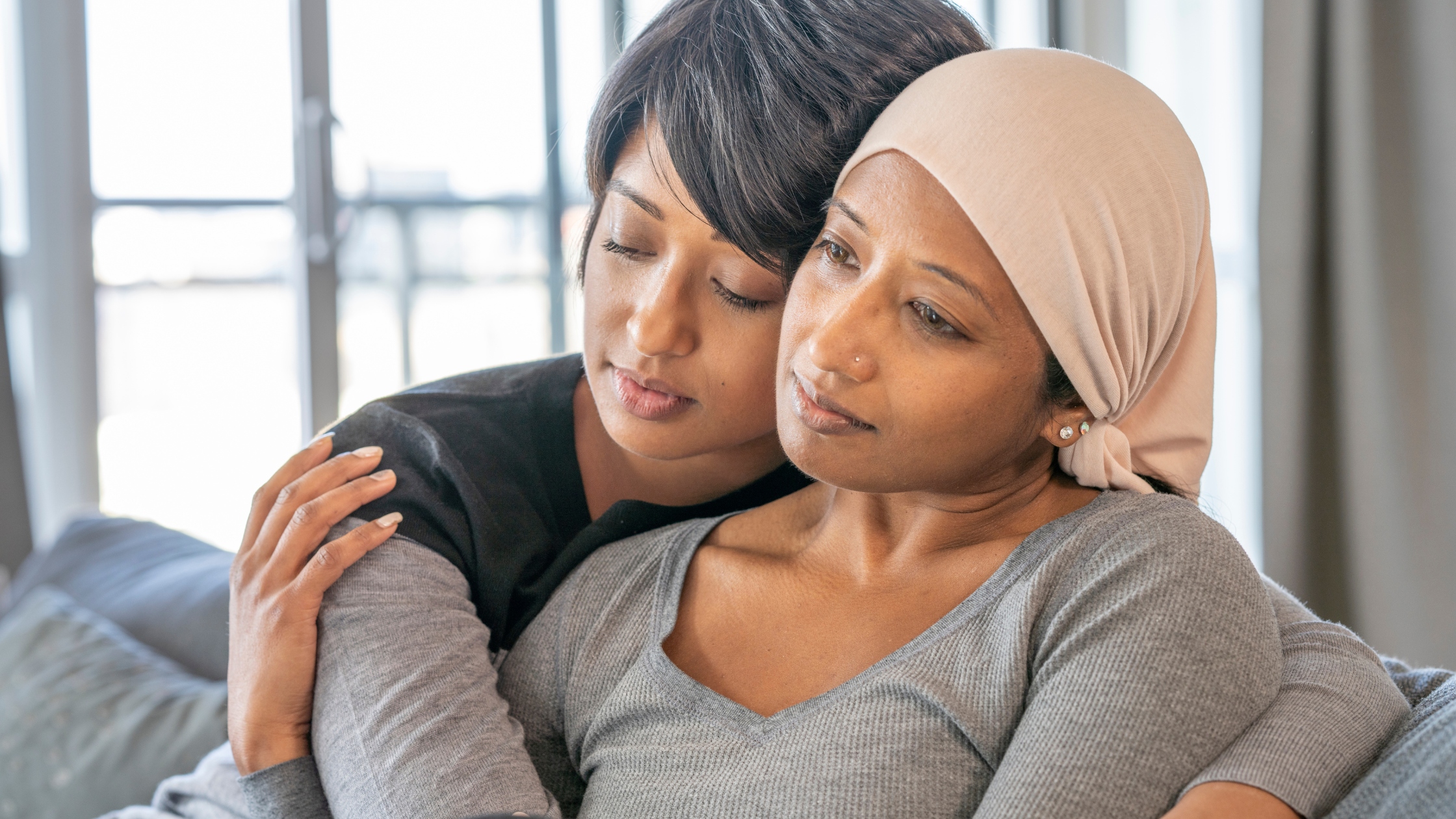 woman with cancer pain hugging younger woman